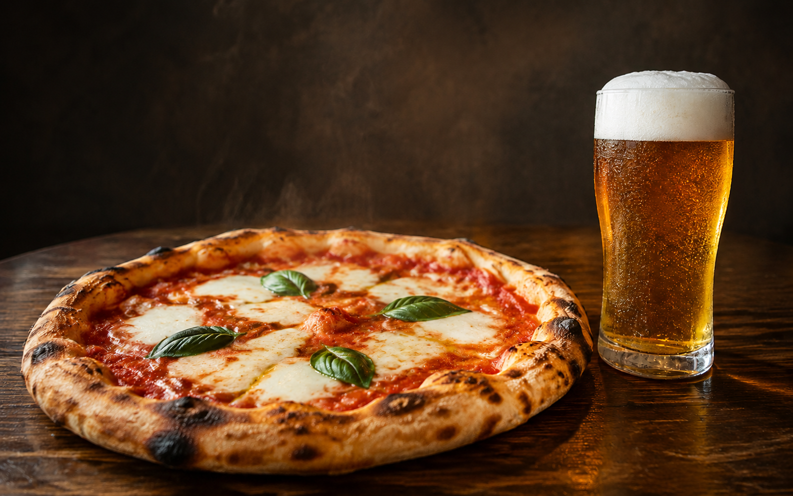 Frisch gebackene Pizza und ein kühles Bier vor einem neutralen dunklen Hintergrund